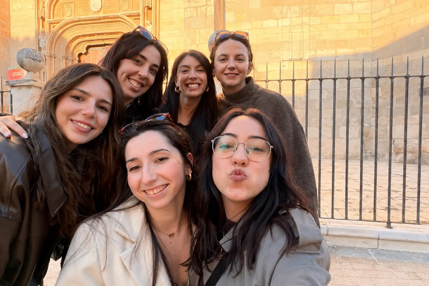 Natalia Pitarch y sus colaboradoras sonriendo juntas frente a un edificio histórico de Alcalá de Henares