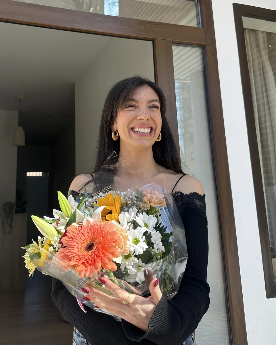 Natalia Pitarch sonriendo con un ramo de flores en la puerta de Reconecta Contigo