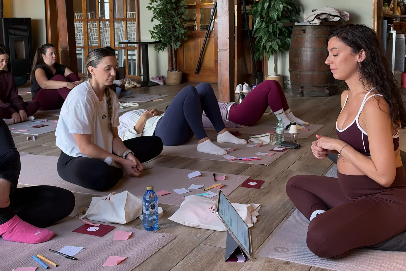 Mujeres sentadas en esterillas durante una experiencia de Reconecta Contigo, con tarjetas y bolígrafos