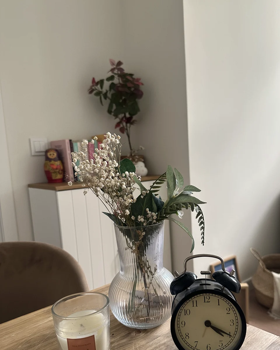 Mesa de la consulta con un jarrón de flores secas, una vela y un reloj despertador